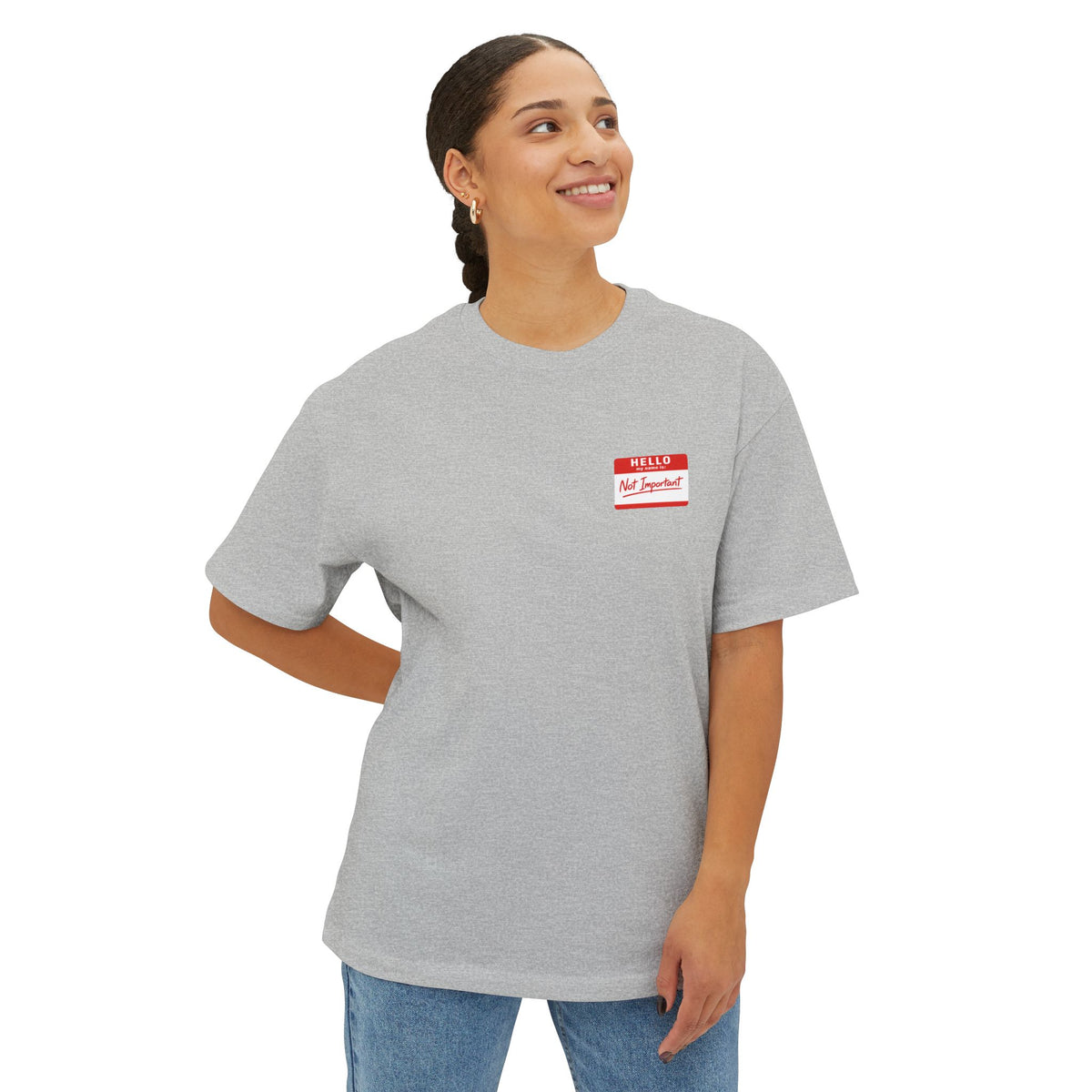 Person wearing a gray t-shirt with a red and white name tag on a white background