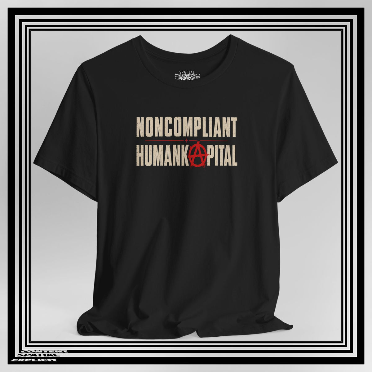 A black short-sleeve t-shirt with the words 'NONCOMPLIANT' and 'HUMANKAPITAL' printed in beige, with a red anarchy symbol replacing the letter A. The shirt is displayed on a white background with a black and white double border.