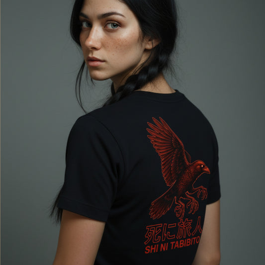 A woman wearing a black t-shirt with a red raven design and text on the back against a gray background